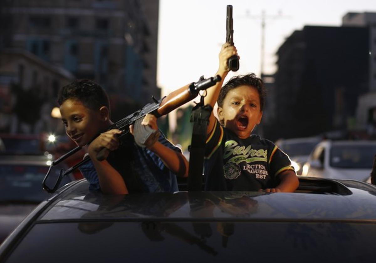 Niños palestinos con armas celebrando el alto el fuego en Gaza