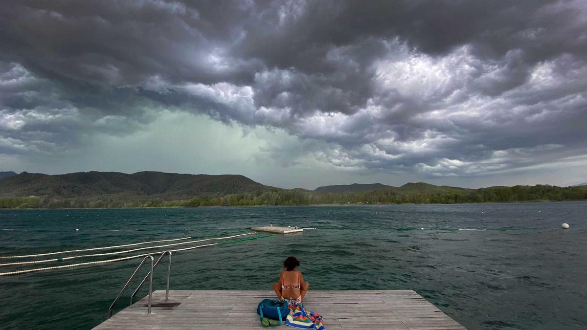 Una dona observa els núvols de tempesta a l'estany de Banyoles.