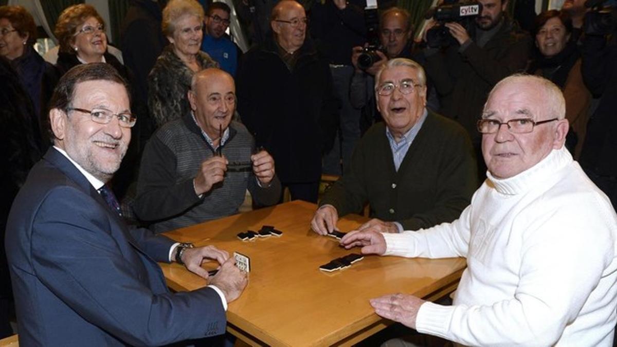 El presidente del Gobierno, Mariano Rajoy, junto a sus compañeros de juego en el Hogar del Pensionista, tras su intervención hoy en un mitin en la localidad vallisoletana de Olmedo.