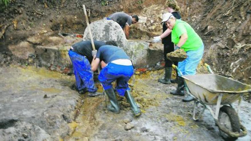 Alumnos del taller de empleo, en plena faena en la fuente de El Güeyu.