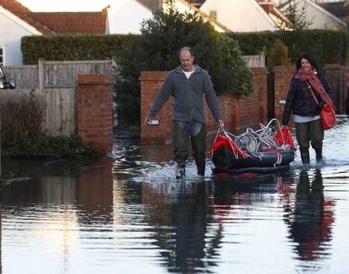 Residents bring back stools in a canoe to raise their furniture higher after the river Thames flooded the village of Wraysbury, southern England