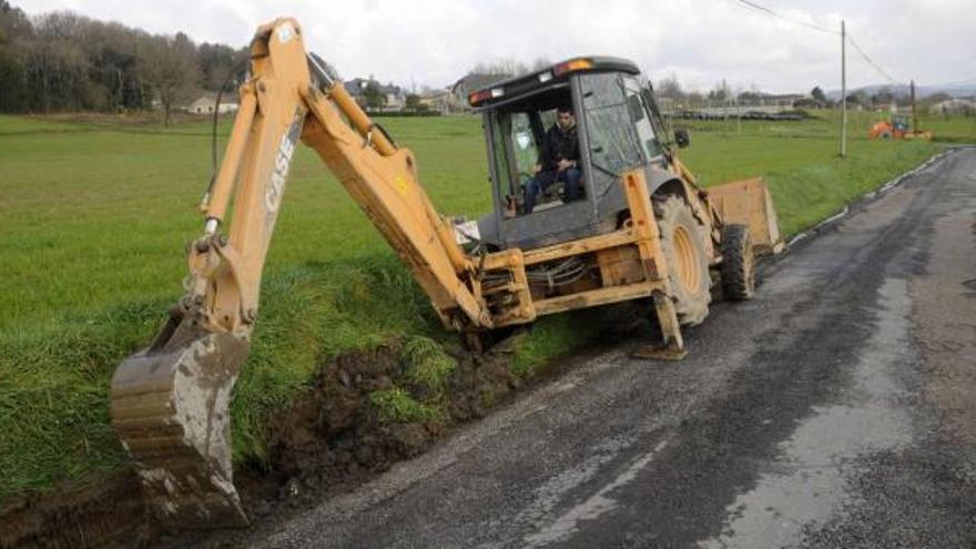 La retroexcavadora de la Mancomunidade prepara desde ayer el terreno para bachear el vial, de 450 metros de longitud .  // Bernabé/Javier Lalín