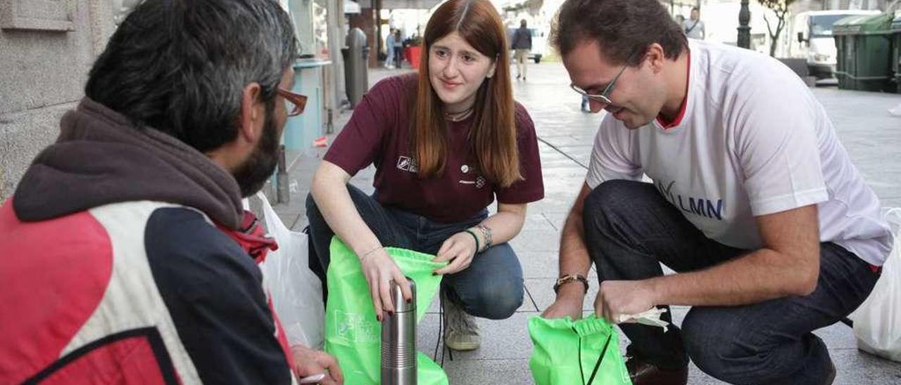 Voluntarios atienden a una persona sin hogar, en Vigo, en el Día Solidario de la Empresa. // FdeV