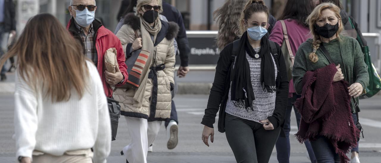 Ciudadanos caminan por la calle con mascarilla