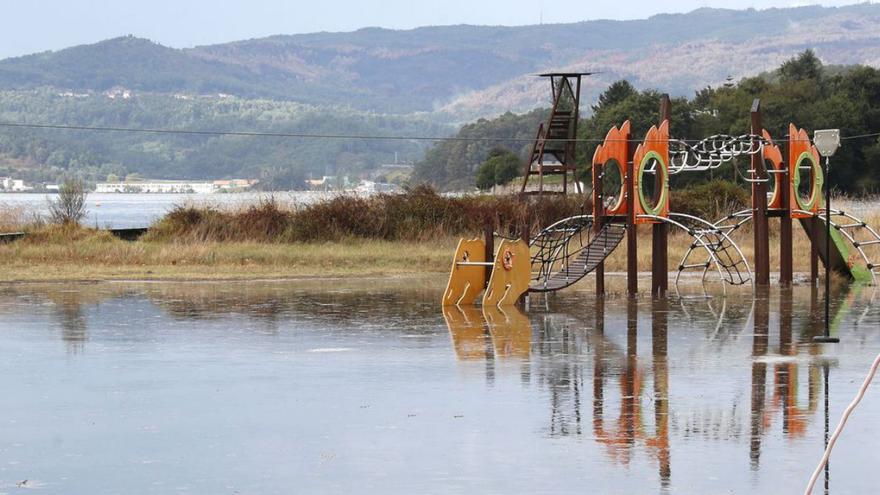 El parque infantil de la playa de Cesantes, ayer, completamente anegado. / José Lores