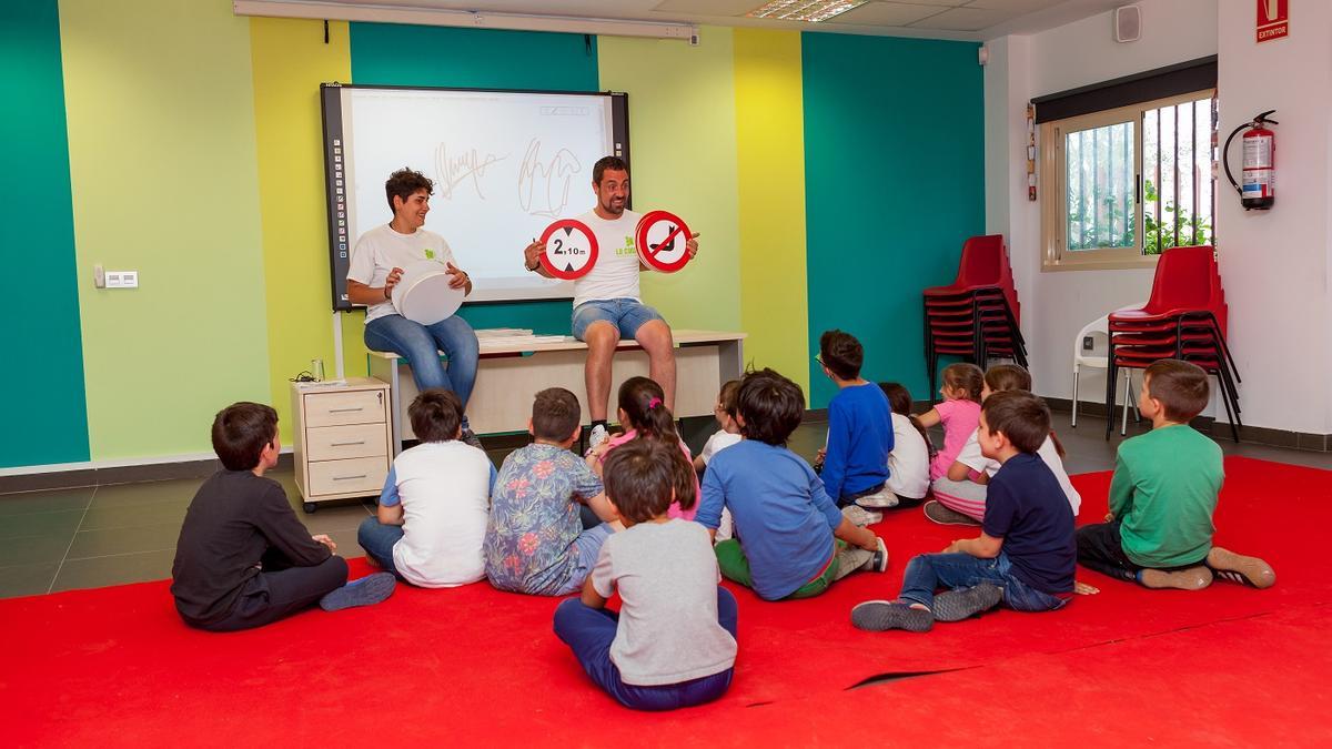 Un par de monitores realiza una clase teórica entre en el parque infantil de tráfico de Mislata.