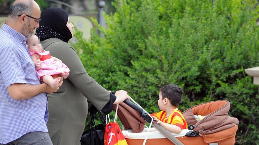 Una mujer con velo lleva en un carricoche a un niño vestido con los colores de la bandera catalana.