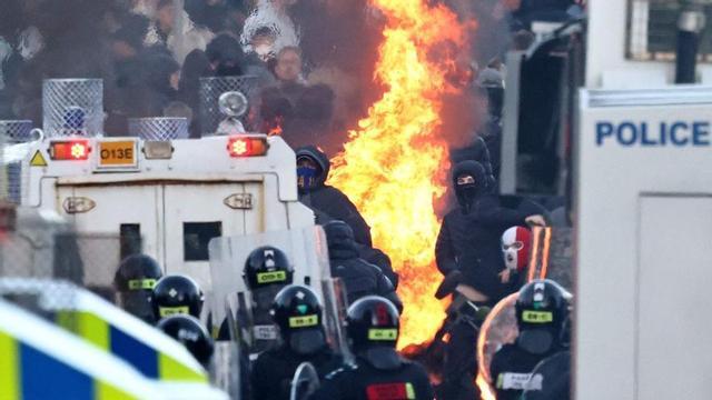 Enfrontaments entre la policia i els manifestants a Glengormley, als voltants de Belfast.La policia impedeix el pas de manifestants cap a un hotel que acull immigrants a Glengormley, al nord de Belfast, en la segona nit de disturbis per l’atac d’un sol·licitant d’asil. | HENRY NICHOLLS / AFP