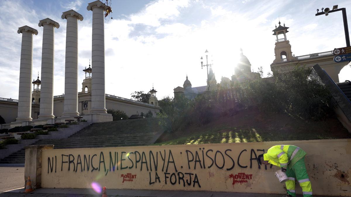 Operarios de limpieza eliminan pintadas en contra de la cumbre hispano-francesa en Barcelona