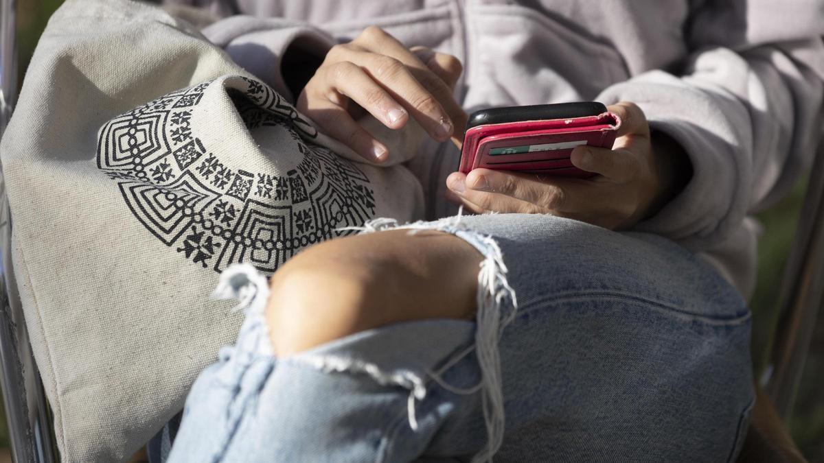 Una menor utiliza su móvil antes de entrar en el instituto.