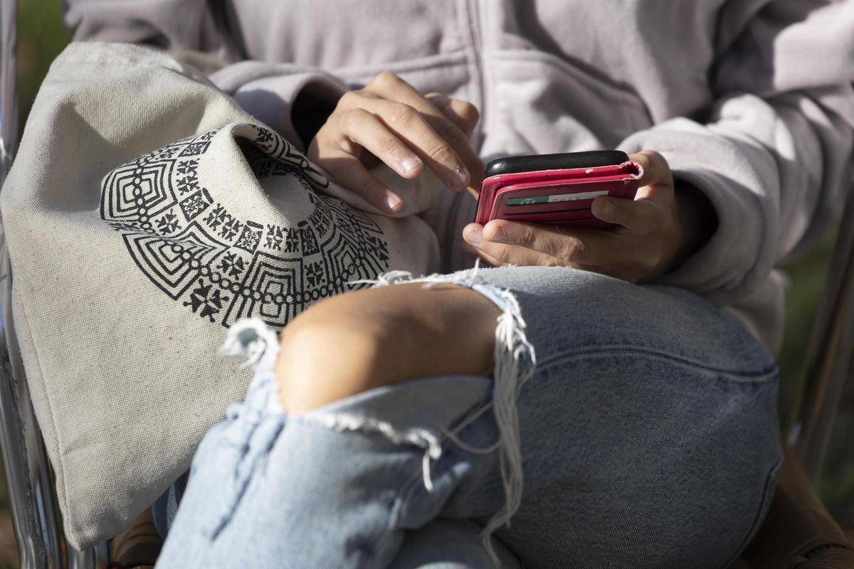 Una menor utiliza su móvil antes de entrar en el instituto.