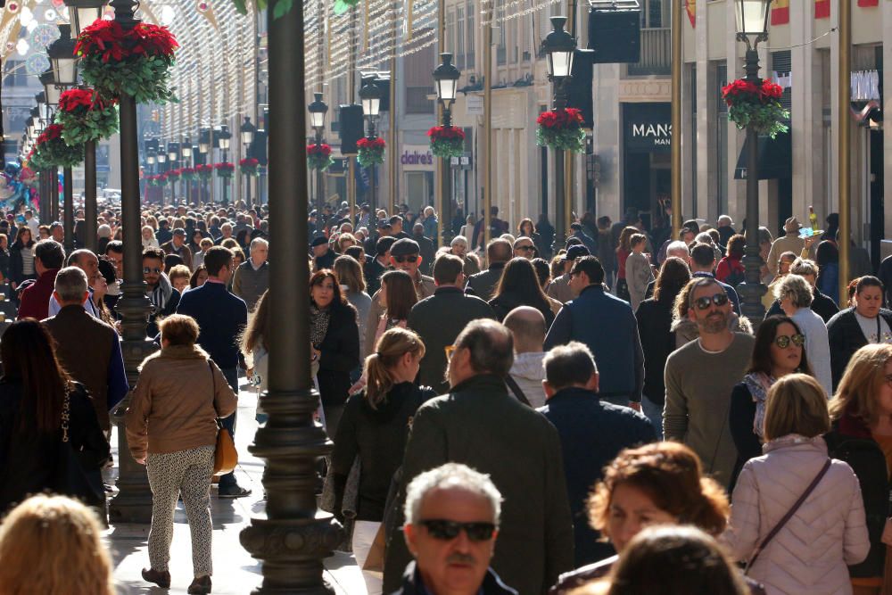 Muchos malagueños y turistas aprovechan el buen tiempo y el día festivo por la Inmaculada Concepción para pasear y realizar las compras navideñas en el Centro de Málaga.