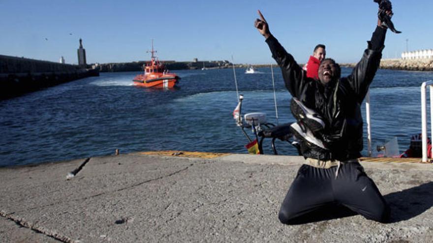 Uno de los inmigrantes alza los brazos a su llegada a puerto, ayer.