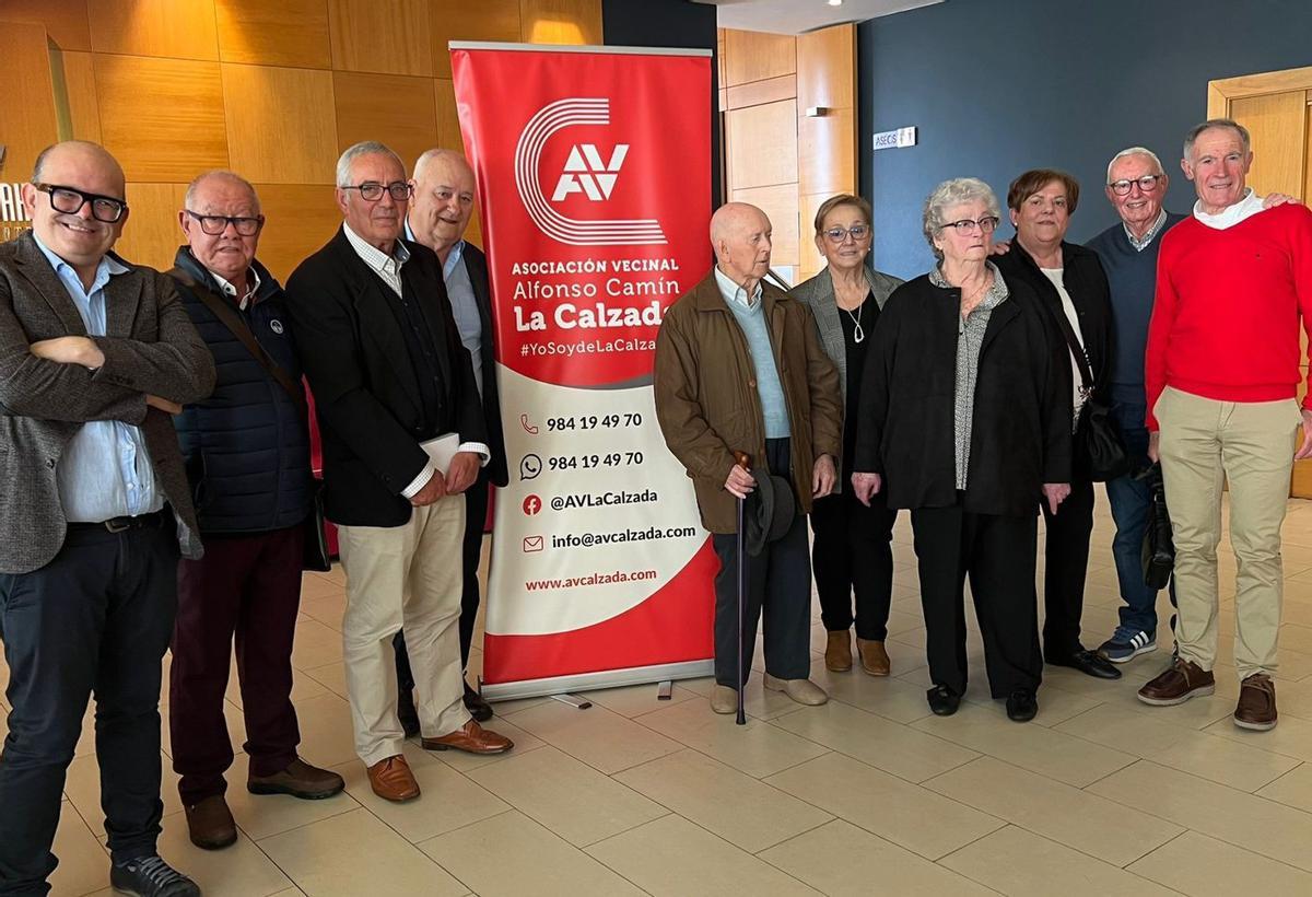 De izquierda a derecha, Carlos Arias, Manuel Arias, Teodosio Pardo «Oviedo», Juan Ramón Rubianes, Manuel Fuentes Carrera, Esperanza Fernández Puerta, Yolanda Cueto, Hortensia «Tensi» Fernández, Daniel Ouviana y Juan Manuel Moreno Cubino posan junto a un cartel de la asociación de vecinos «Alfonso Camín» de La Calzada (Gijón).  | LNE