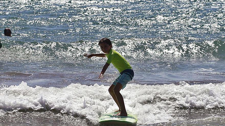 Un alumno surca el mar con su tabla.