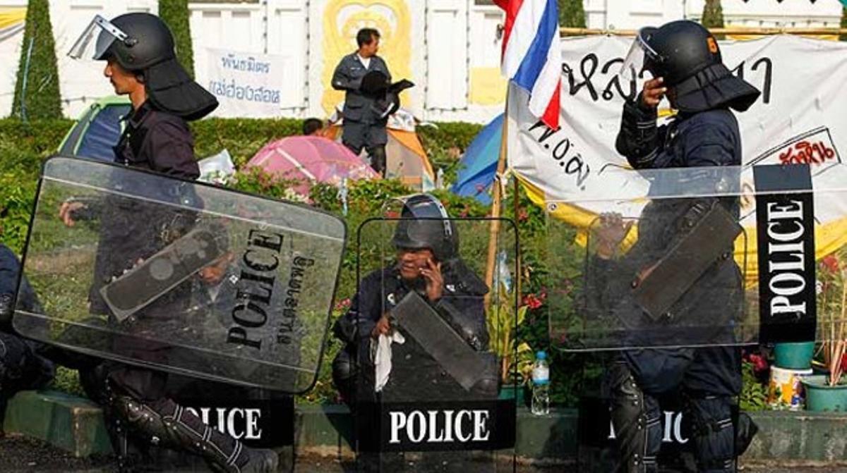 Uns policies s’agafen un descans durant la marxa dels partidaris de l’Aliança Popular per la Democràcia, a prop de la seu governamental a Bangkok.