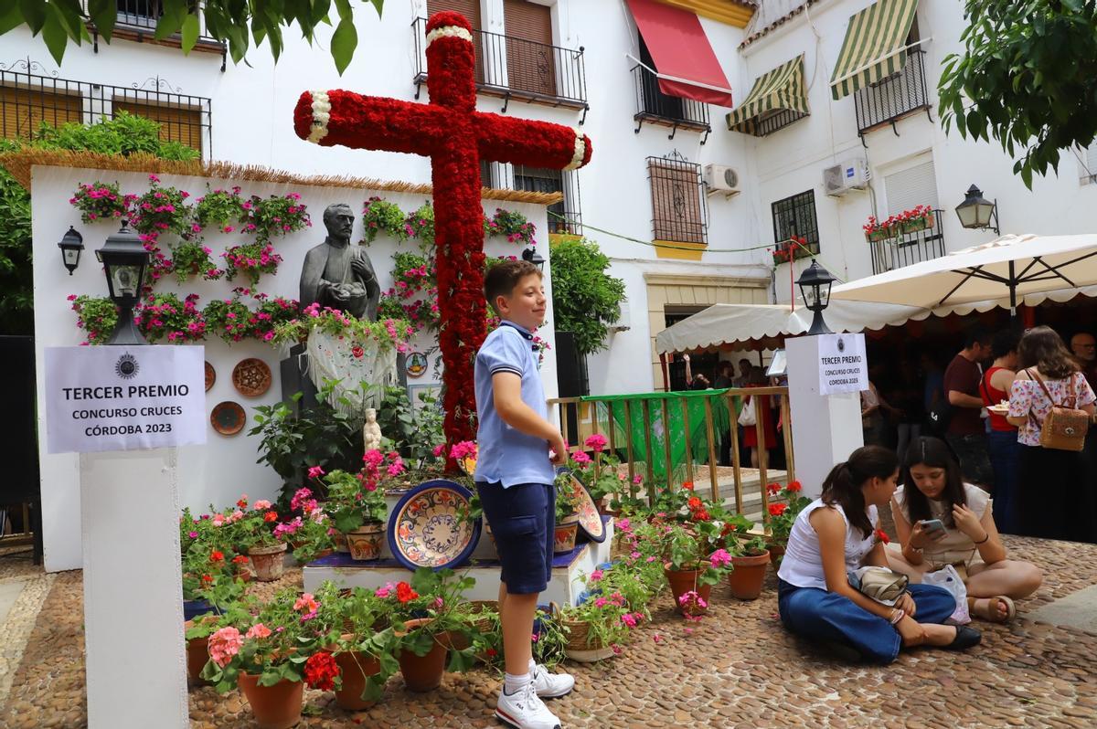 Un niño se toma una foto en la cruz de la plaza del Padre Cristóbal, que monta la hermandad de Jesús Nazareno.