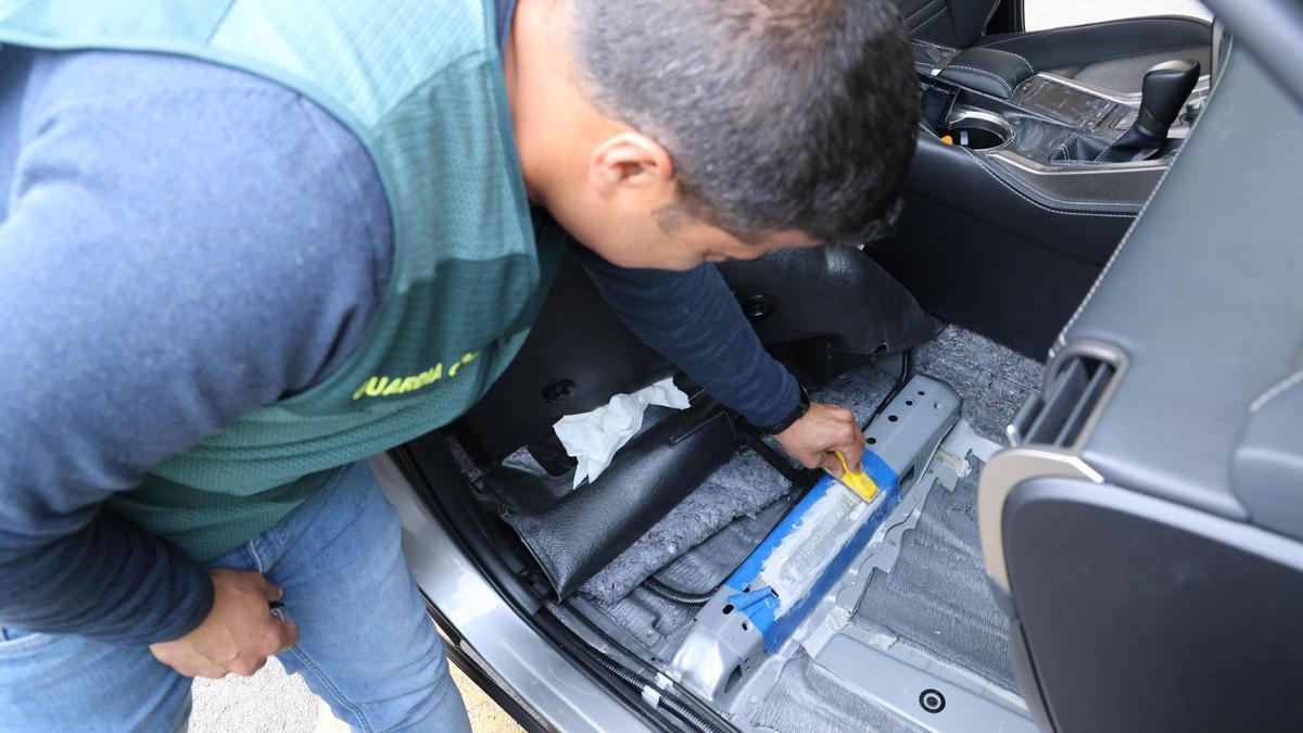 Un agente de la UCO muestra el bastidor manipulado en un Lexus robado en Alicante.