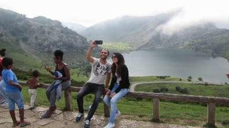 Turistas haciéndose fotos con el lago Enol al fondo.