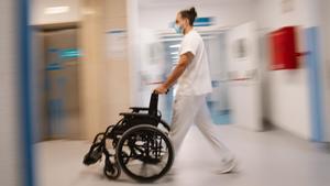 Un celador lleva una silla de ruedas en el Hospital de Móstoles.