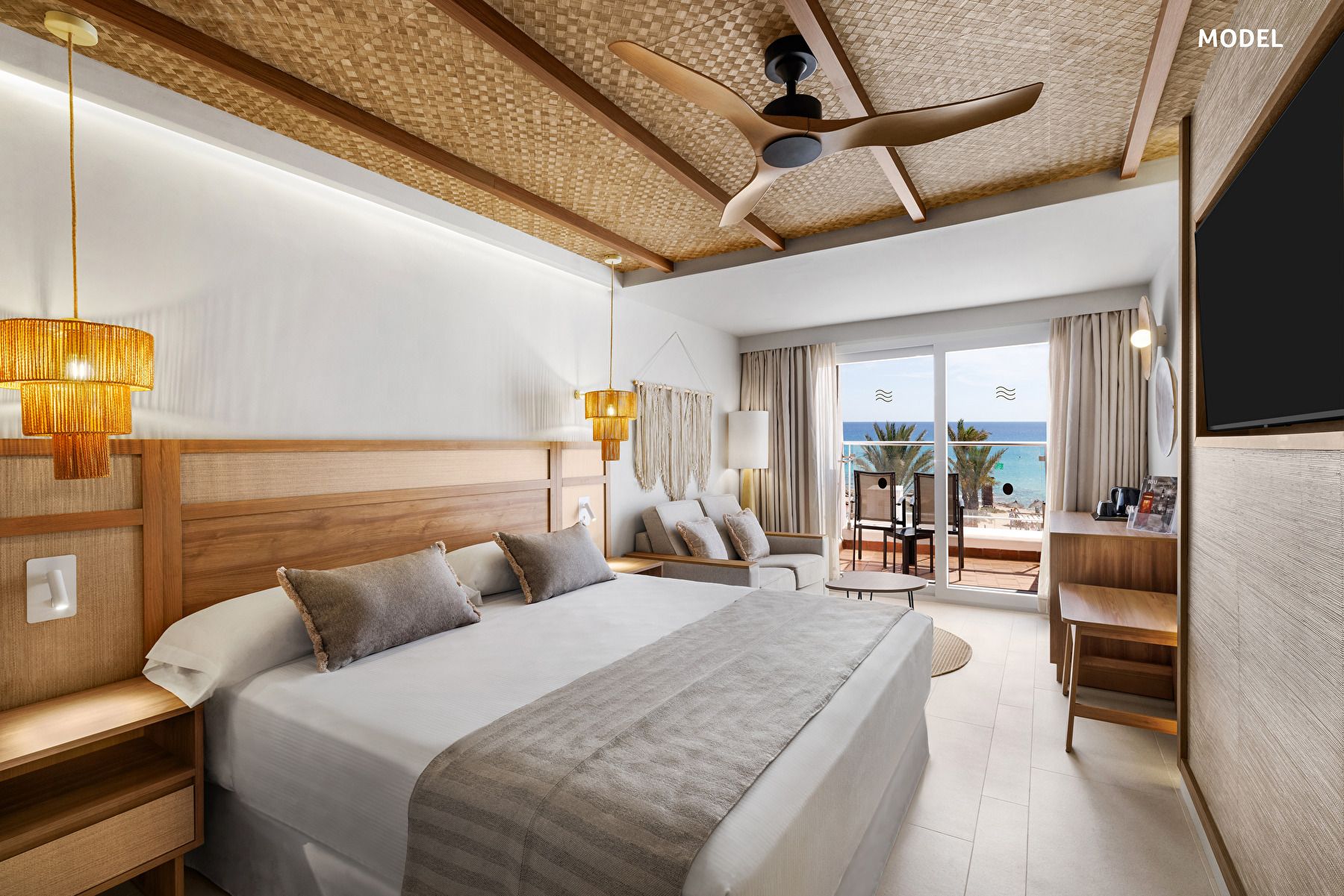 Habitación doble con cama, sofá y vistas al mar.