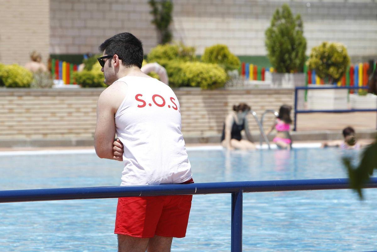 Un socorrista apoyado en la valla de una piscina en Zaragoza