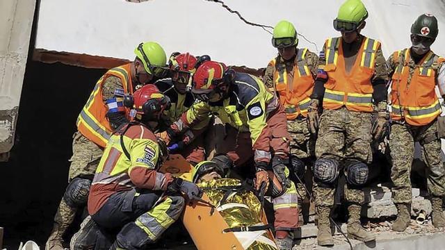 Membres dels equips de rescat de la Brigada de Bombers de Quito rescaten un supervivent a Caraballeda, a prop de La Guaira.  | BRIGADA DE BOMBERS DE QUITO / FRANCE PRESSE