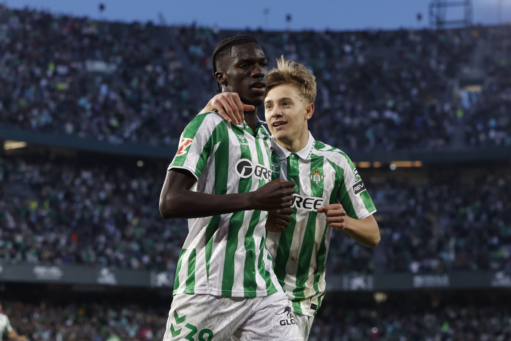 El delantero español del Betis Assane Diao (i) celebra con su compañero Jesús Rodríguez (d) tras marcar el 2-2 durante el partido de la jornada décimo sexta de LaLiga EA Sports que disputaron Real Betis Balompié y FC Barcelona en el Estadio Benito Villamarín de Sevilla. EFE/ Julio Muñoz. (Betis)