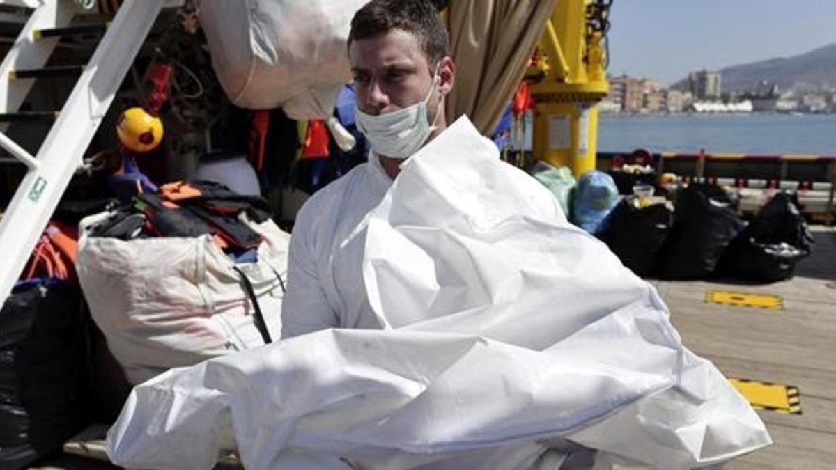 Un hombre transporta un cadáver a bordo del buque 'Responder' gestionado por la Cruz Roja y por MOAS, una oenegé de Malta, en el puerto de Trapani (Sicilia).