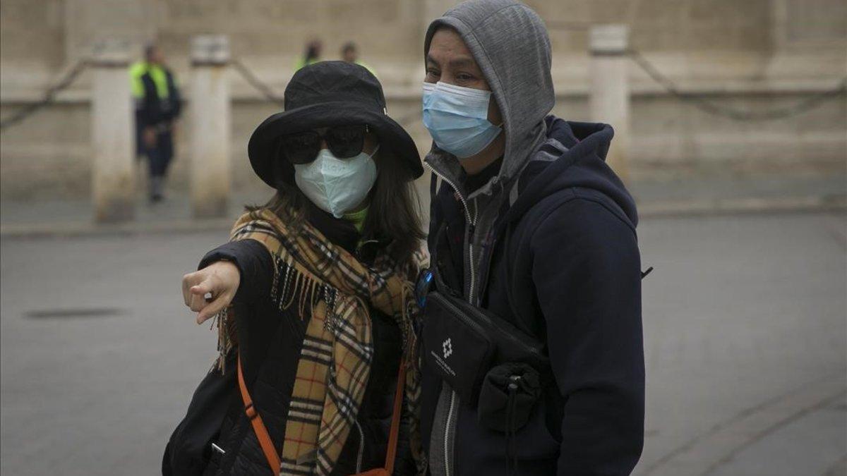 Turistas con mascarillas para protegerse del coronavirus pasean por Sevilla