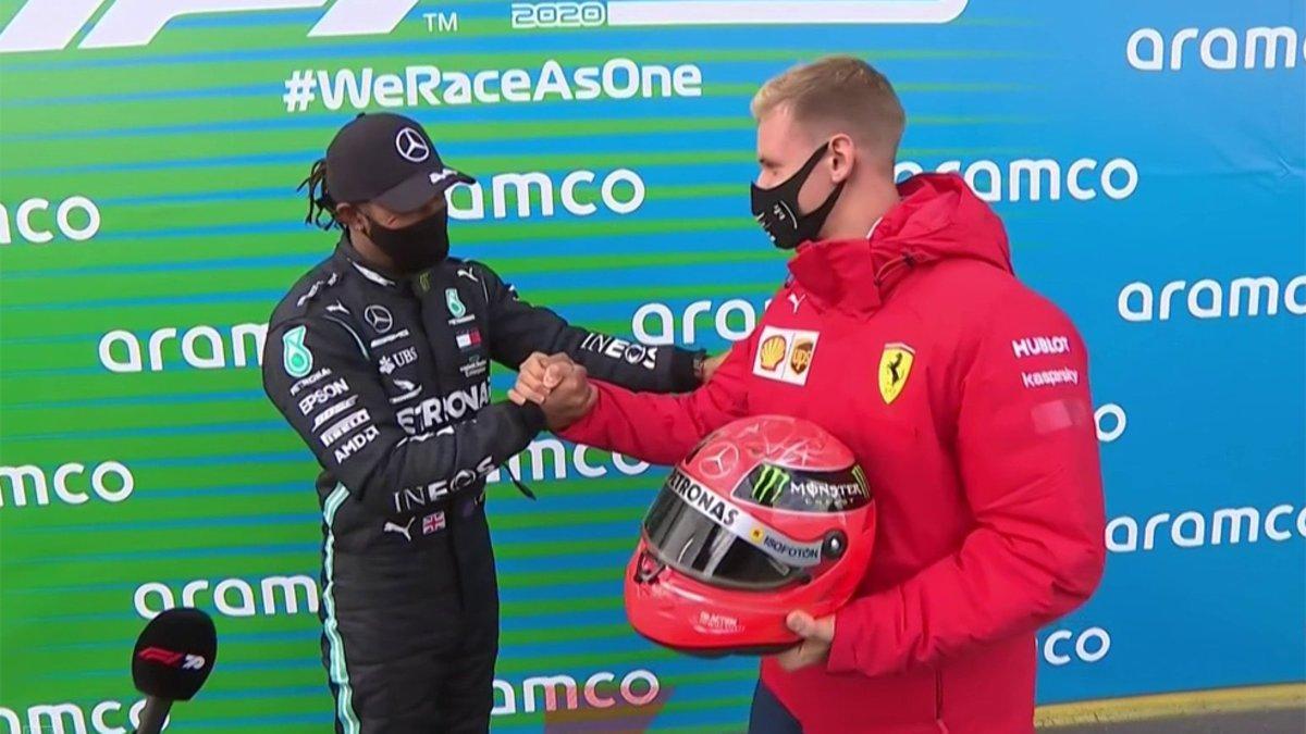 Mick Schumacher en el momento que le hace entrega del casco a Lewis Hamilton
