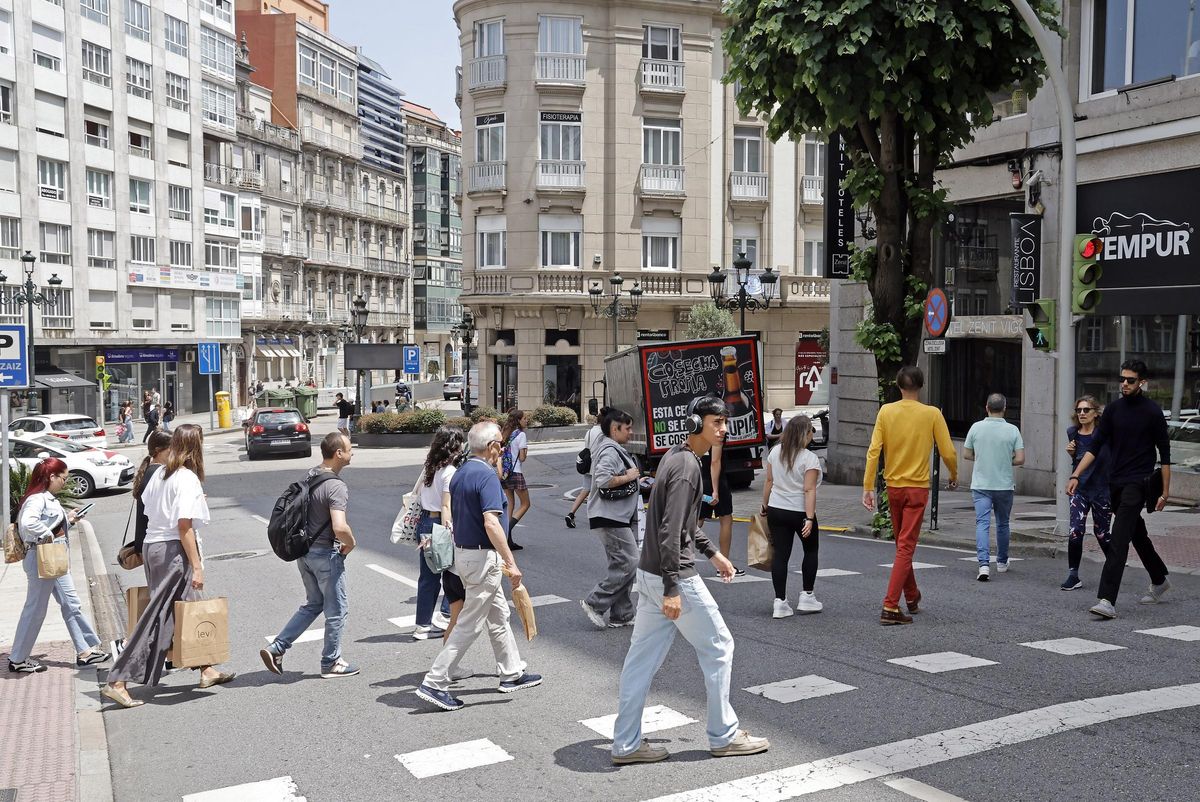Peatones cruzando la carretera con el semáforo en verde en la calle Gran Vía de Vigo