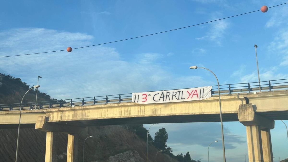 Pancarta en la A-7 reclamando un tercer carril para disminuir los frecuentes atascos. | LA OPINIÓN