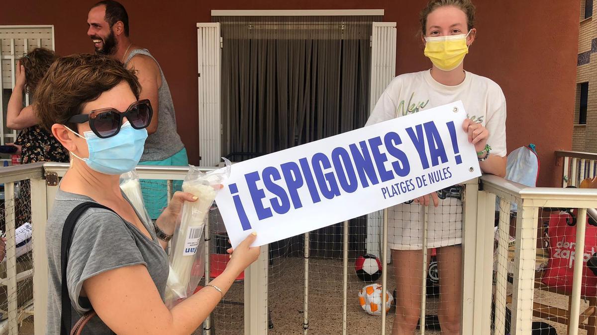 Reparten entre los vecinos de la playa carteles reivindicativos para que los cuelguen de balcones y terrazas.