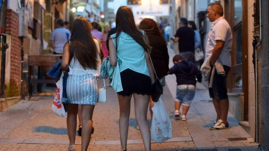 Dos jóvenes con bolsas de bebidas por la calle.