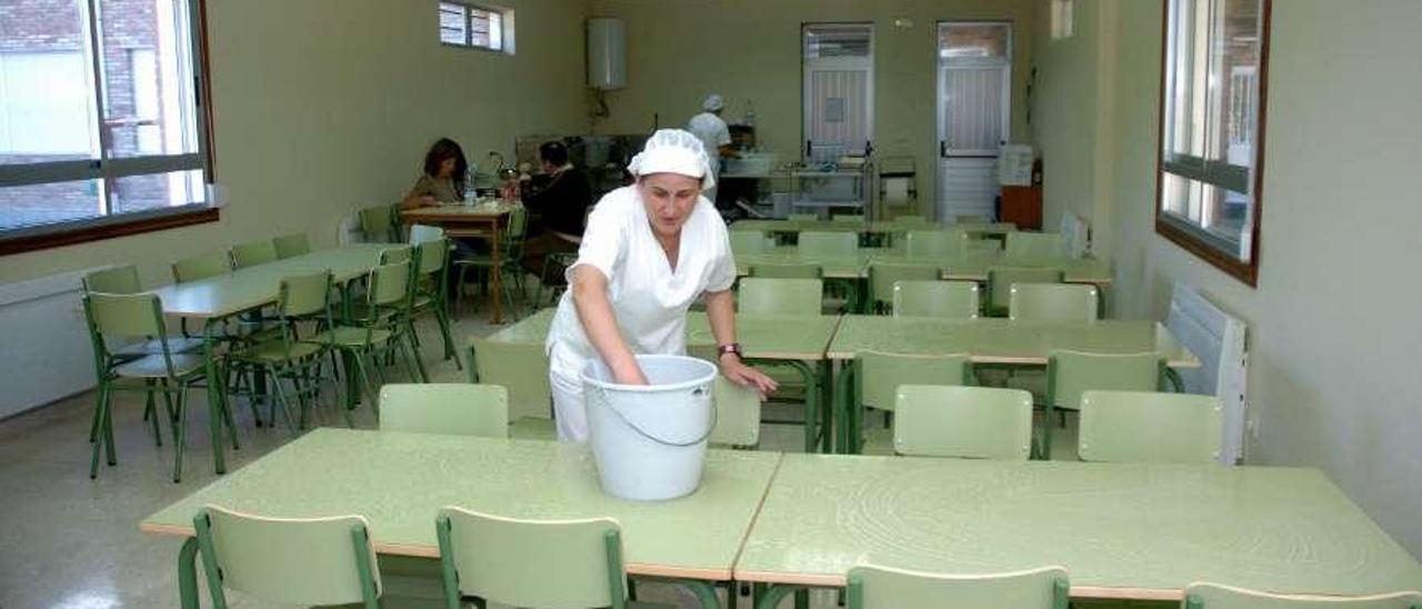 Una trabajadora limpia unas mesas en el comedor del colegio de San Clemente.