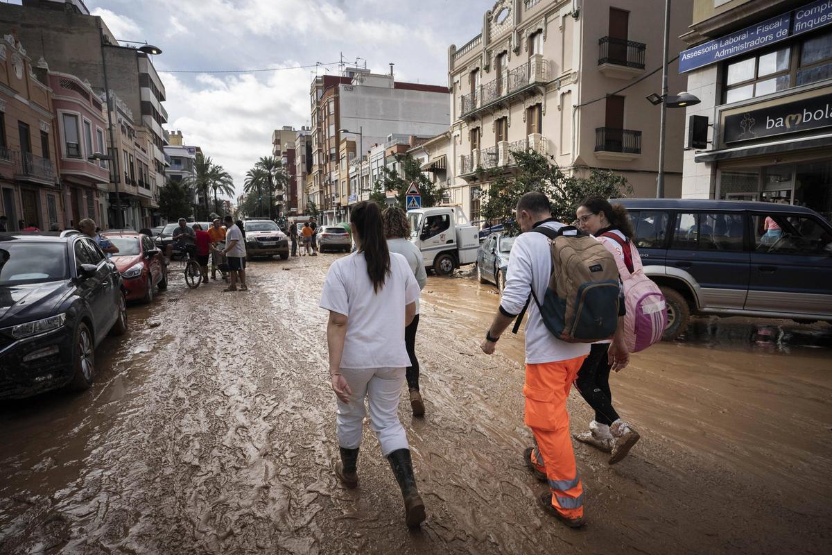 Voluntaris i veïns s’afanyen a netejar un carrer a Catarroja l’1 de novembre de 2024.