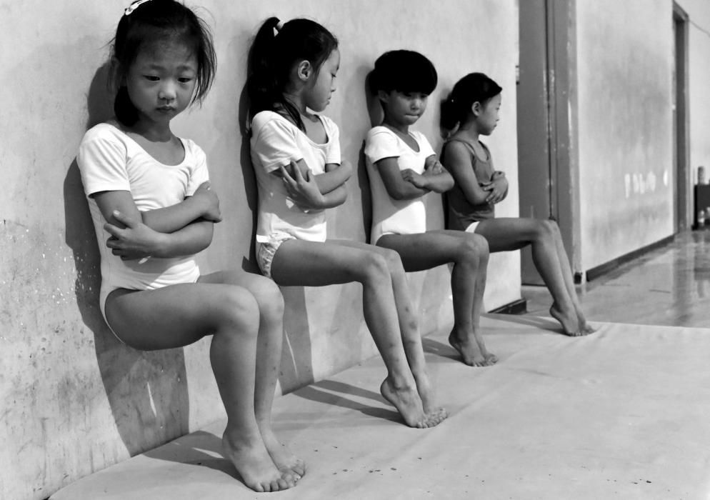 Quatre estudiants de l'escola de gimnàstica realitzen flexions dempeus durant un entrenament a Xuzhou (Xina).