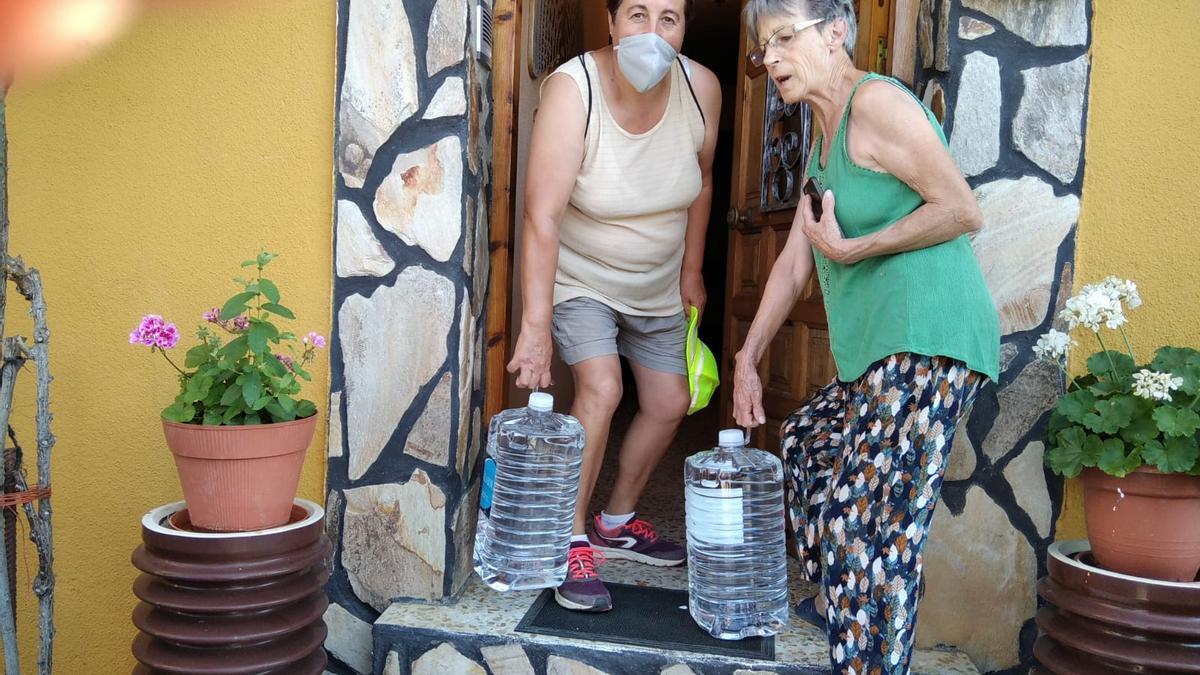 Dos mujeres acarrean garrafas de agua a su domicilio en agosto de 2020, tras detectarse arsénico en el pozo de sondeo de Junquera.