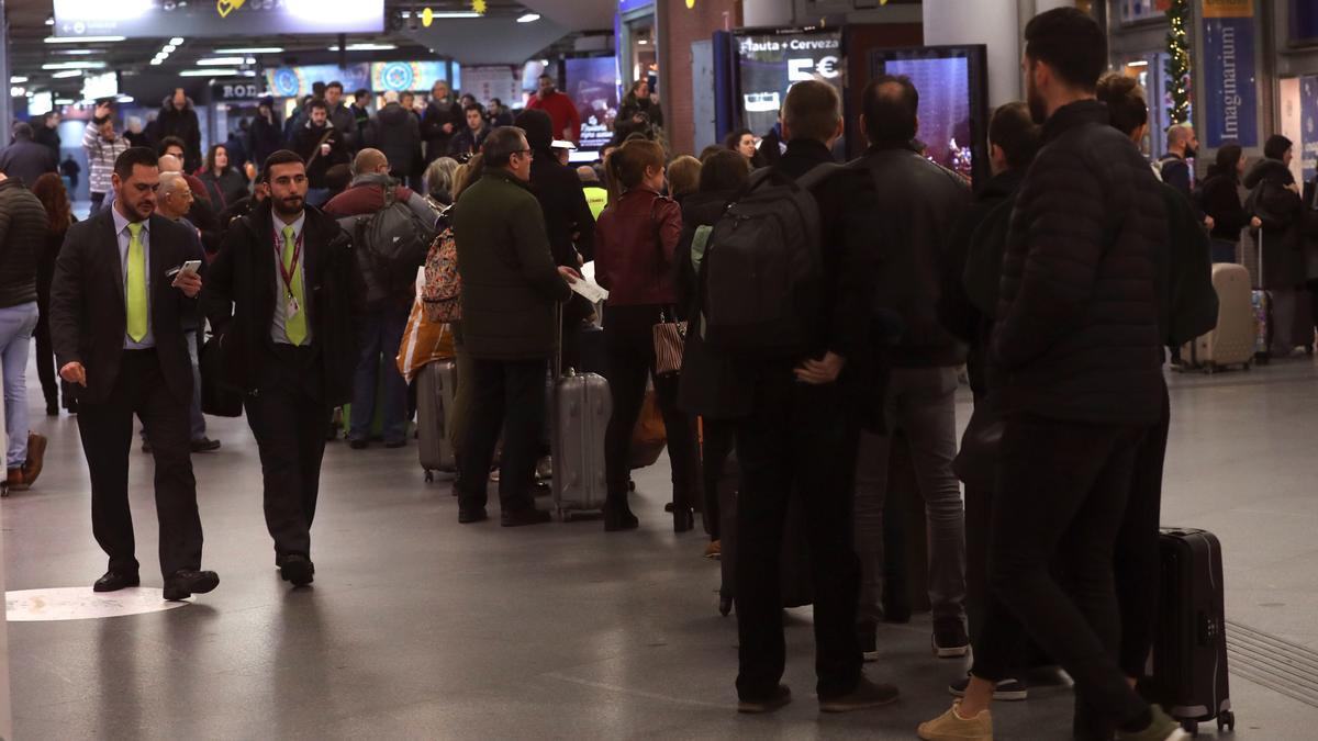 Varias personas hacen cola en una estación.