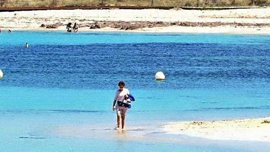 Una mujer pasea por la orilla de la playa de es Pujols ayer por la tarde mientras, al fondo, otros se bañan.