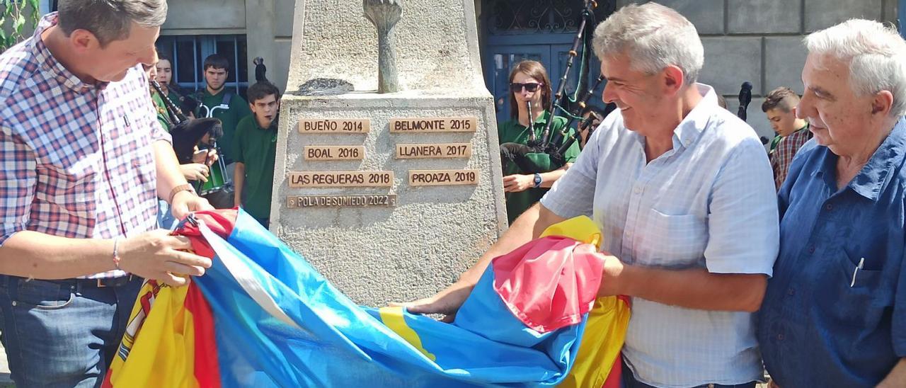 Los alcaldes de Tineo y Somiedo, José Ramón Feito y Belarmino Fernández, respectivamente, descubren la placa de Pola de Somiedo en el monolito del Día de los Pueblos de Navelgas, con el fundador de la fiesta, el pintor Manolo Linares, a la derecha. | S. Arias