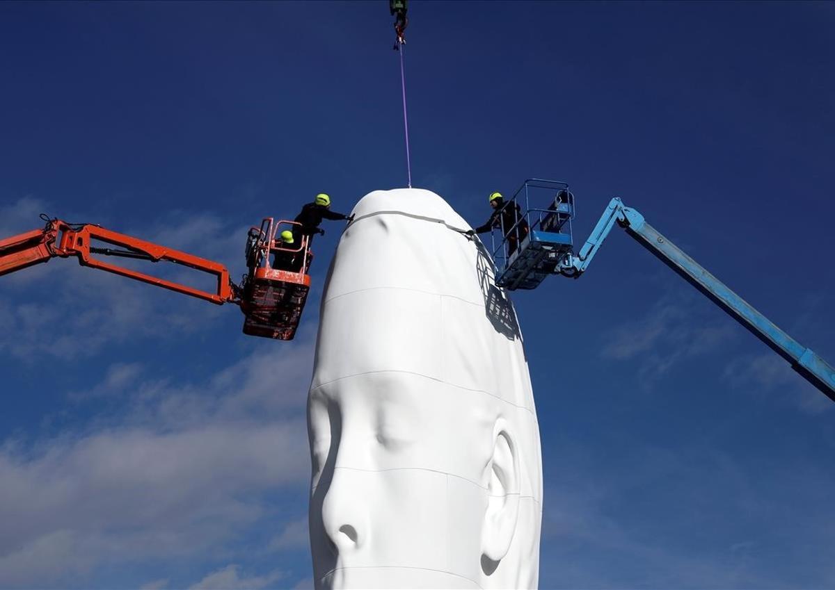 Trabajadores colocan los últimos detalles en la estatua Júlia del artista Jaume Plensa, en la plaza de Colón en Madrid