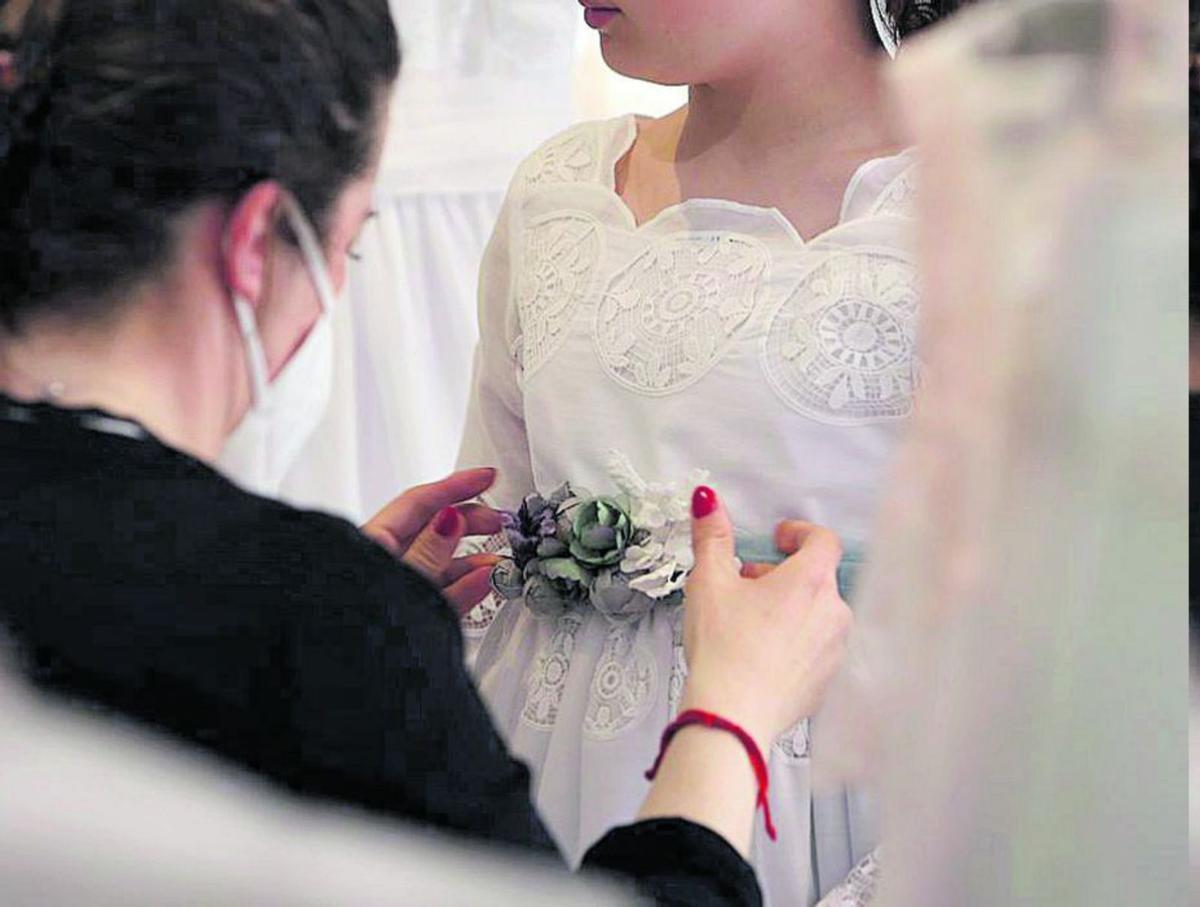 Una madre da los últimos retoques al traje de comunión de su hija