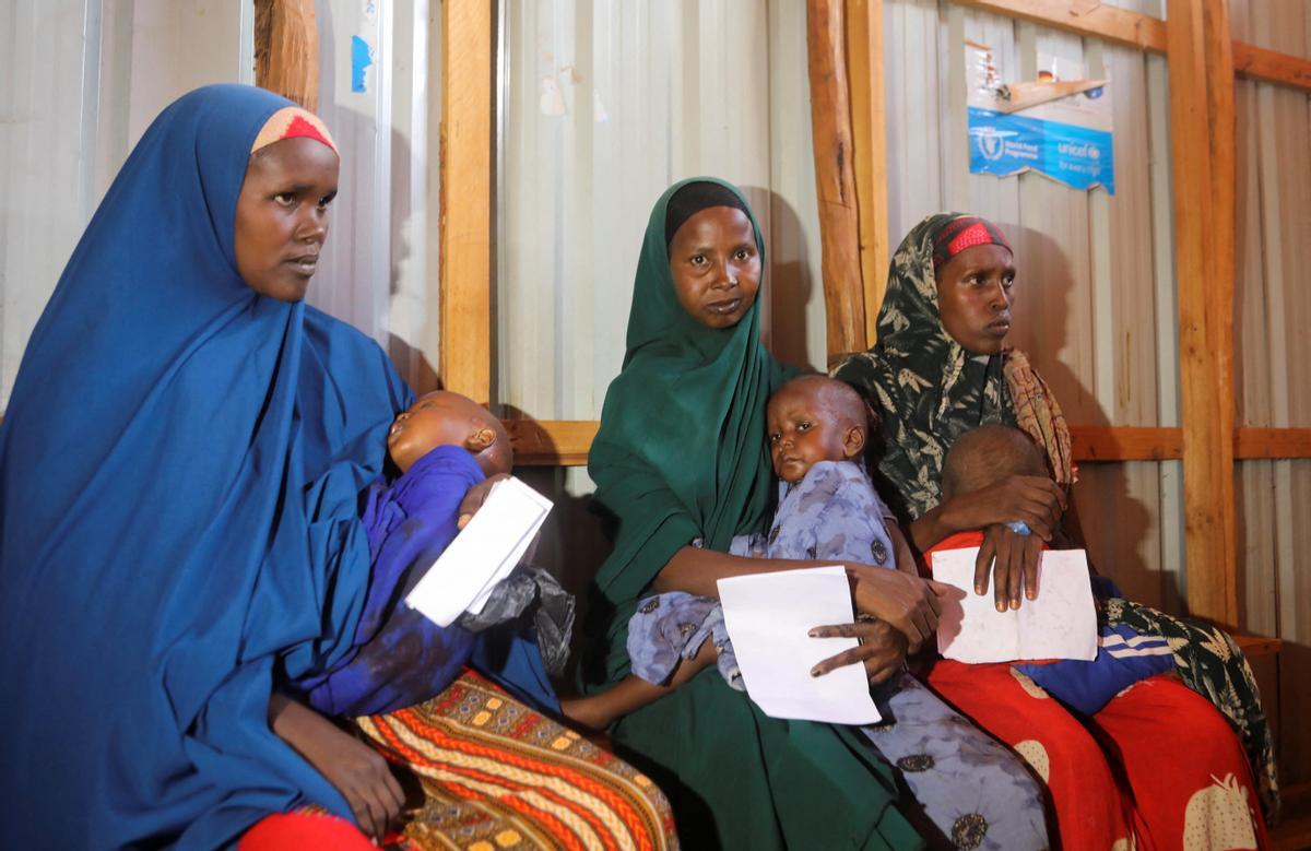 Las mujeres somalíes desplazadas internamente llevan a sus hijos mientras esperan el examen.