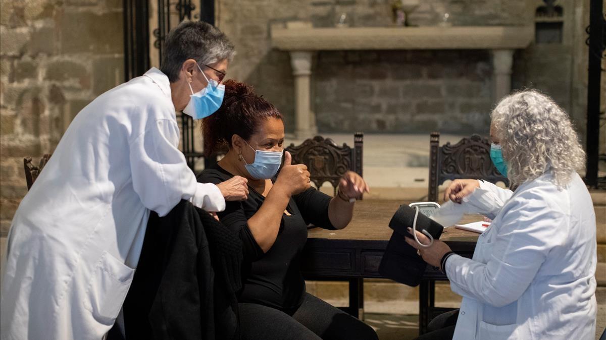 GRAFCAT4159  BARCELONA  09 11 2020 - Una mujer es atendida por dos sanitarias este lunes en la parroquia de Santa Anna de Barcelona donde cada dia se ofrece un comedor social para 120 personas en situacion vulnerable  ademas de servicios medicos y psicologicos gratuitos una vez por semana  EFE Marta Perez