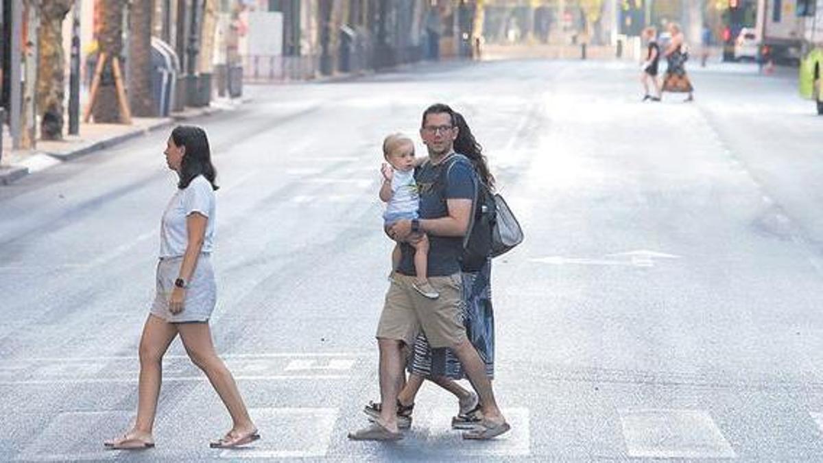 Una peculiar escena veraniega de una familia cruzando una solitaria y céntrica avenida