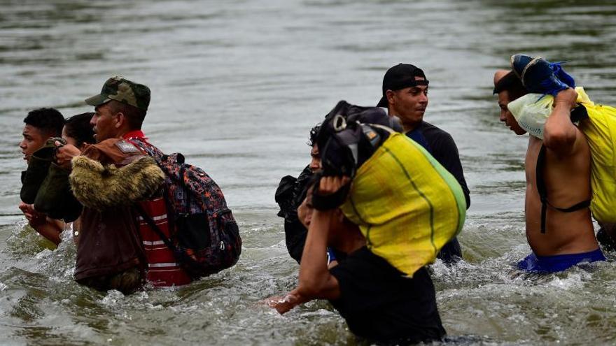 Migrantes hondureños cruzan un río.