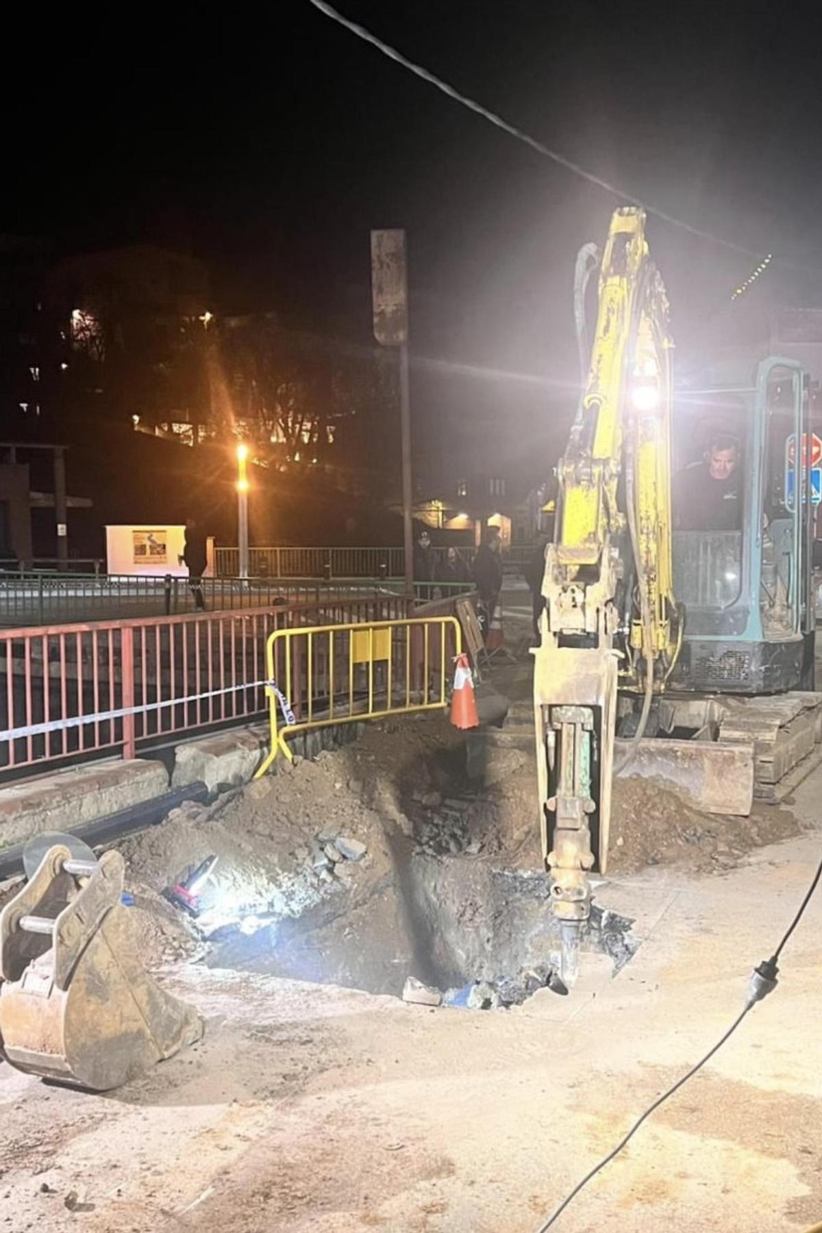 Una màquina treballa en la reparació del nou tram de canonada d'aigua trencada al carrer del Pla de la Coma d'Anglès