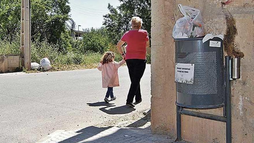 Una vecina de Binissalem transita junto a una papelera donde se ha depositado basura incorrectamente.